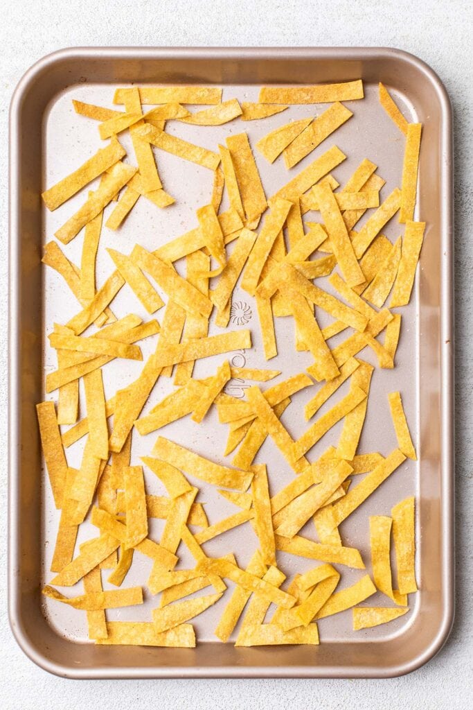Crispy baked tortilla strips on a baking sheet.