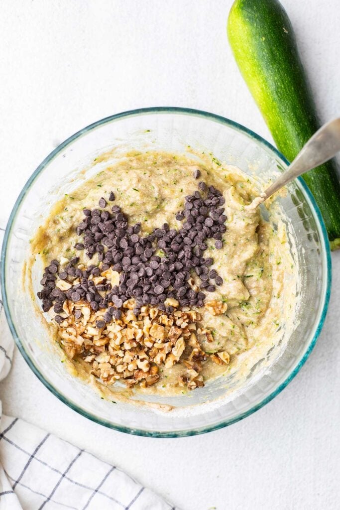 Walnuts and mini chocolate chips being stirred into the muffin batter.