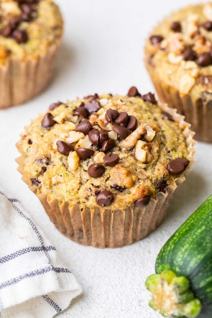 Buckwheat muffins sitting on a counter next to a zucchini.