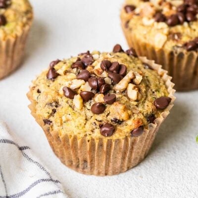 Buckwheat Zucchini muffins shown sitting on a counter next to a zucchini.