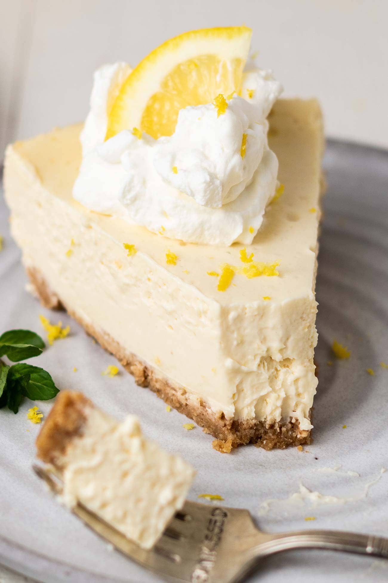 A slice of lemon cheesecake shown with a bite taken out of the end.