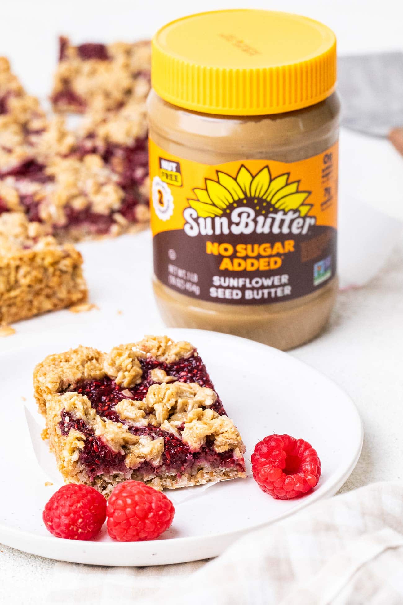 A raspberry bar on a plate next to a jar of SunButter.