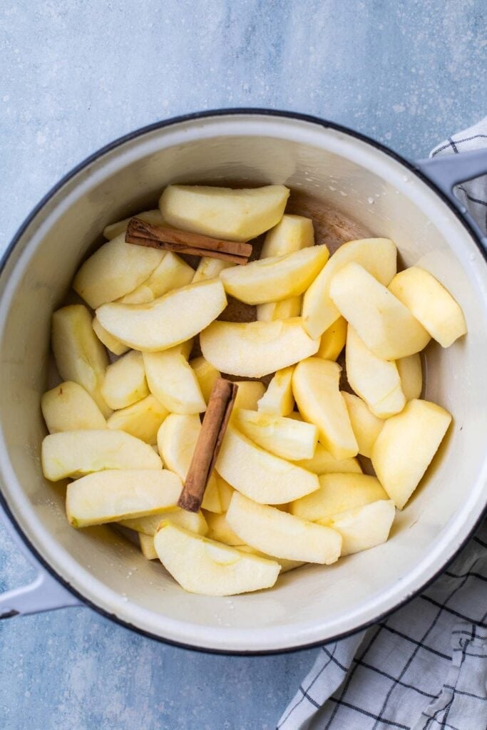 A pot with apples and cinnamon sticks.