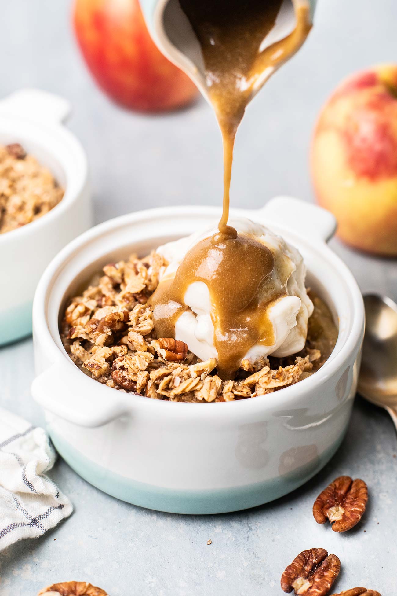 Caramel sauce being drizzled onto ice cream on top of an applesauce crisp.