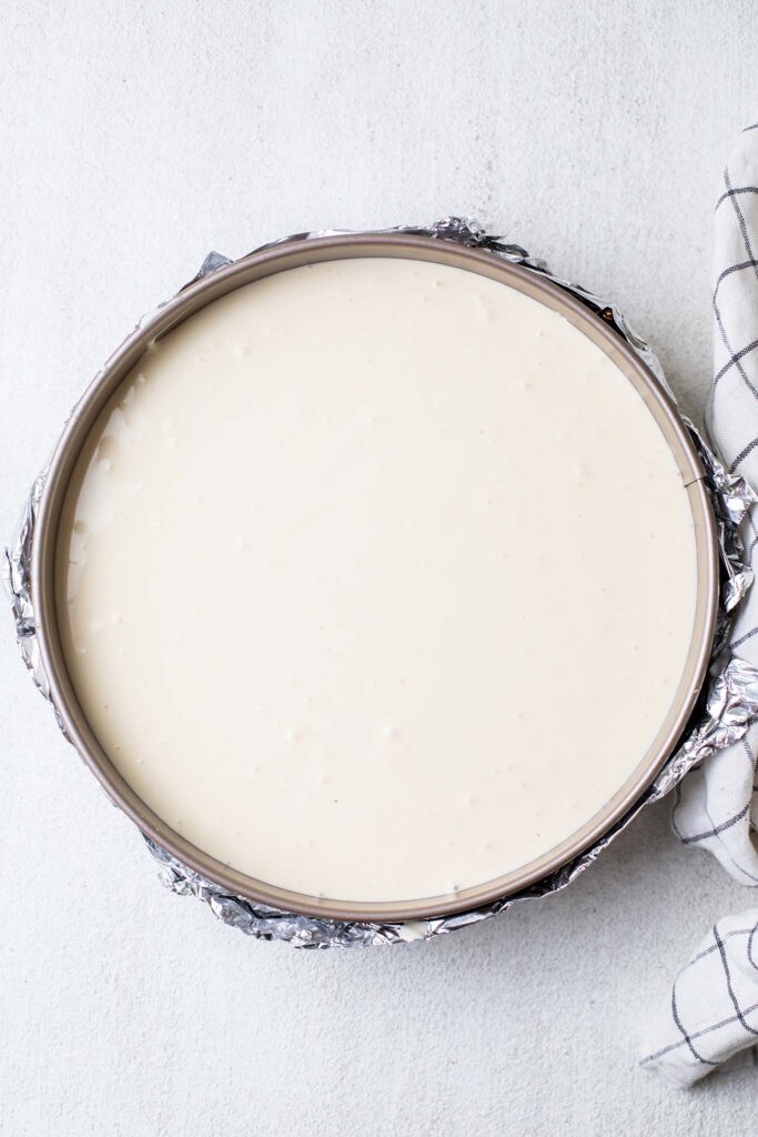 Cheesecake batter poured on top of the graham cracker crust in the springform pan.