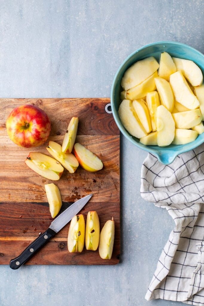 A cutting board with apples being sliced and peeled.