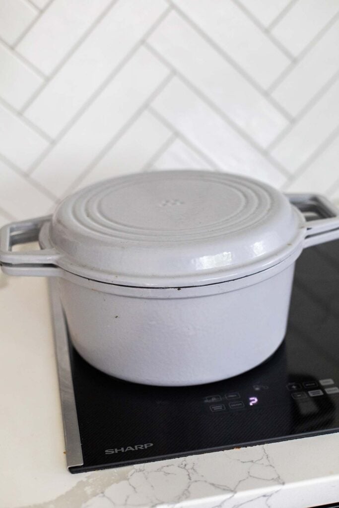 A pot shown on the stove with the lid on.