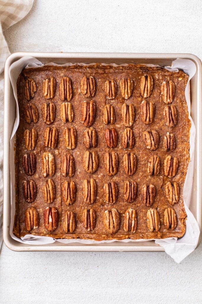 Pecans laid out on top of the caramel layer.