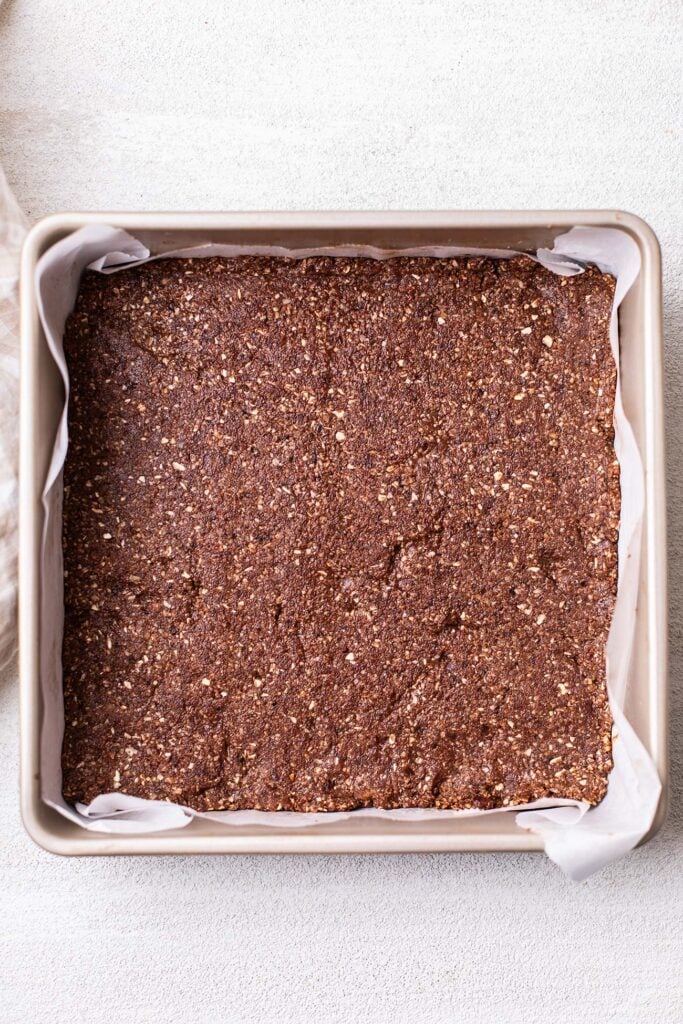 Chocolate cookie dough pressed into a layer in the baking pan.