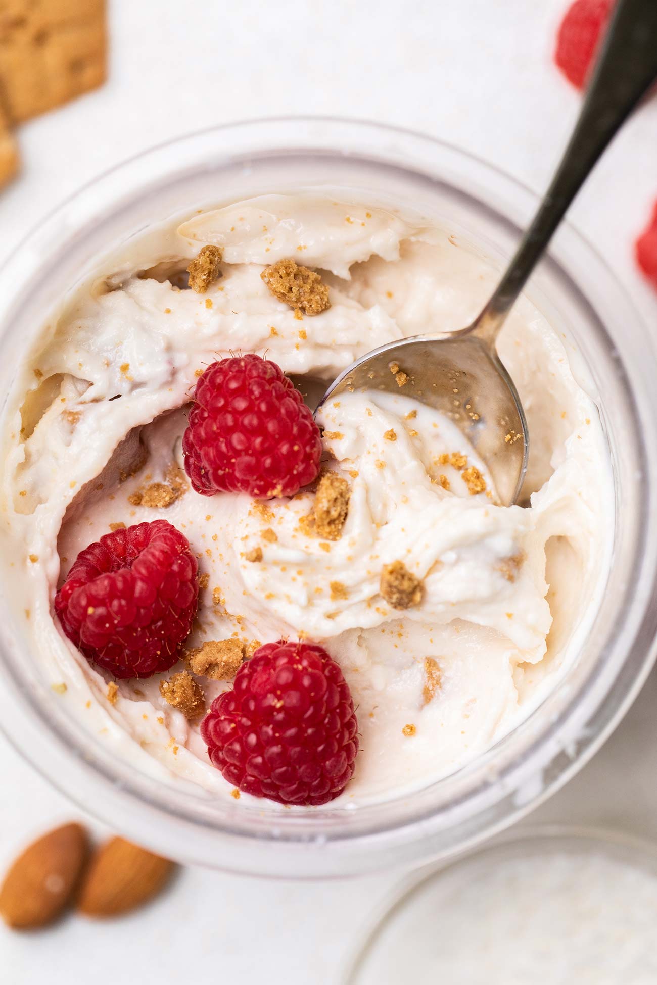 A ninja creami pint container shown with a creamy vanilla ice cream garnished with raspberries.