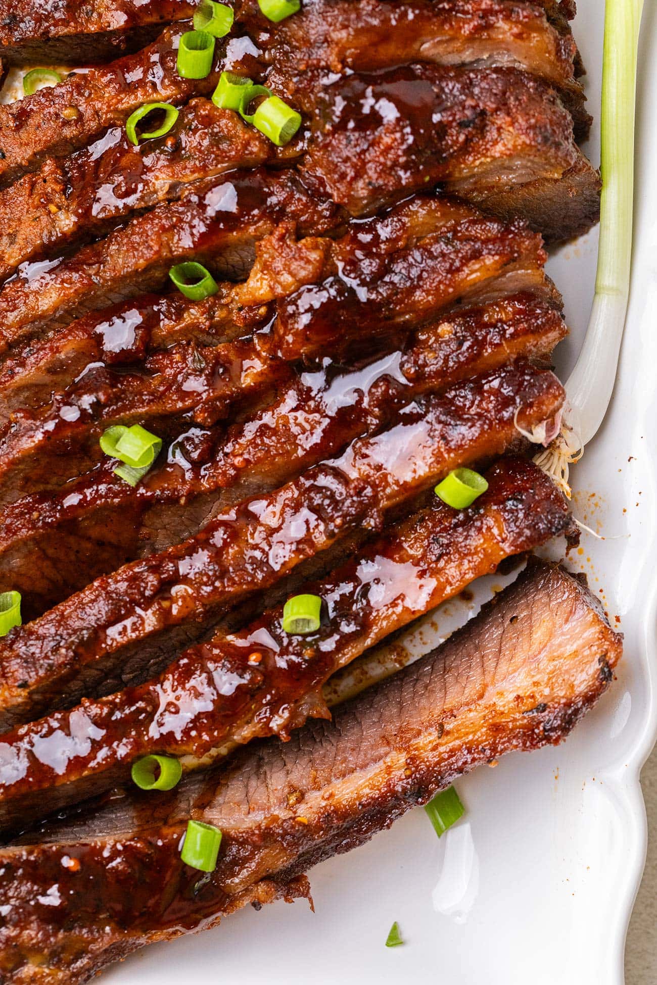 A sliced baked beef brisket shown on a white platter.