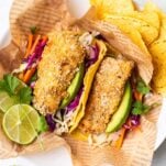 Crispy cod pieces on top of corn tortillas with a colorful cabbage slaw.