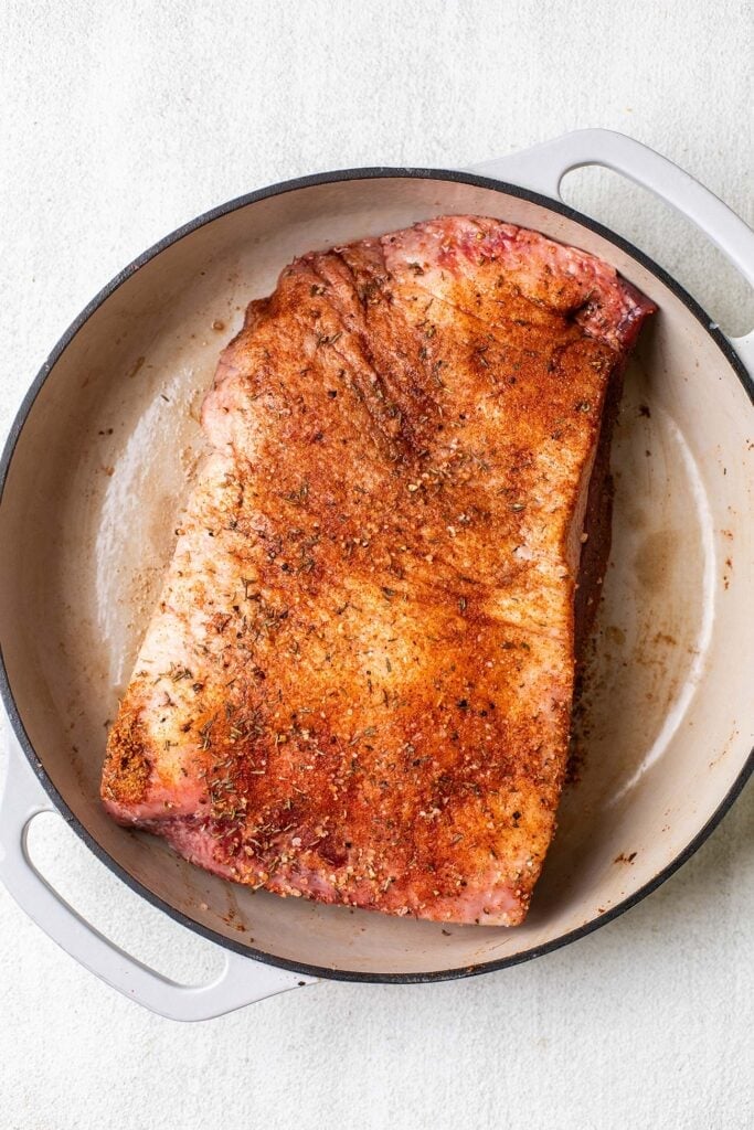 A marinated brisket shown in a cast iron pot.