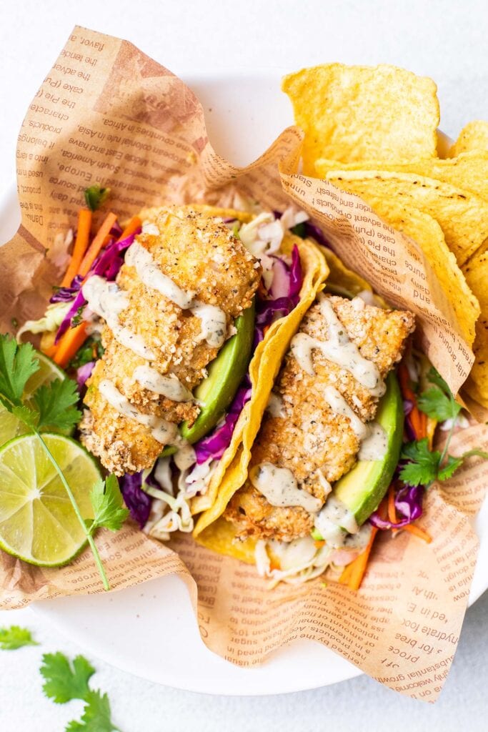 Crunchy air fryer fish tacos shown garnished with avocado and a creamy jalapeno ranch dressing.