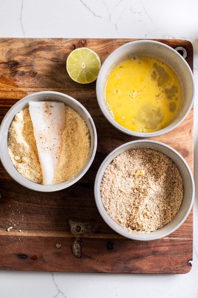 A piece of cod being coated with almond flour.