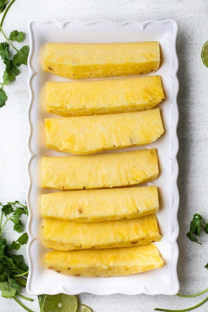 Pineapple cut into long spears on a plate.