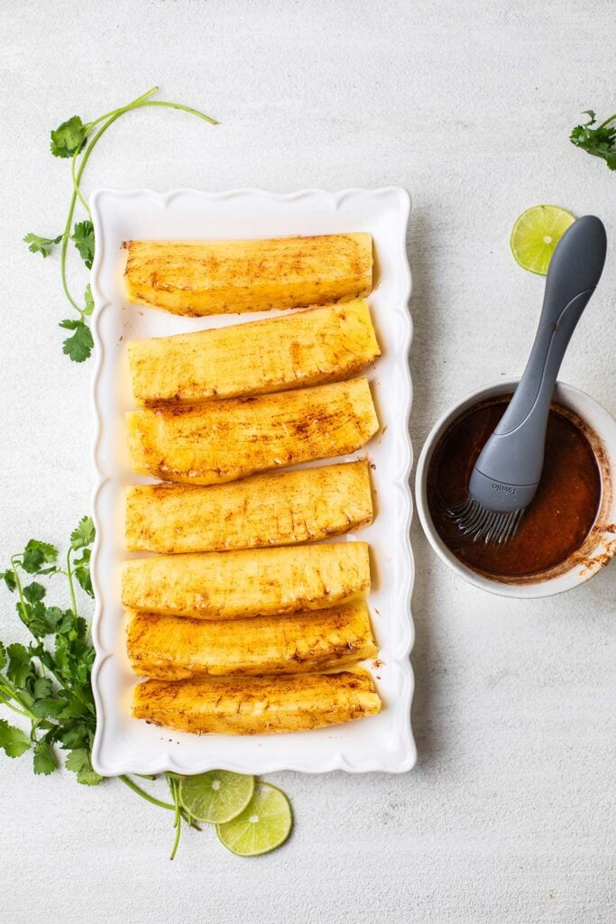 Pineapple being brushed with a spicy cinnamon mixture.
