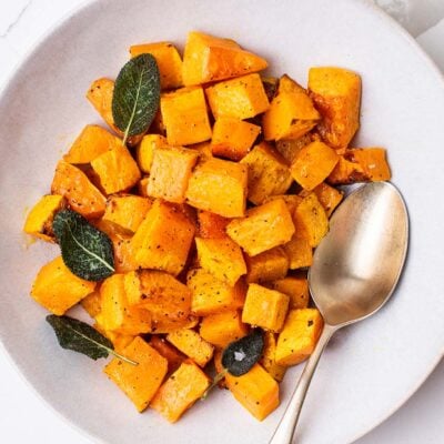 A bowl of air fryer butternut squash garnished with crispy sage.