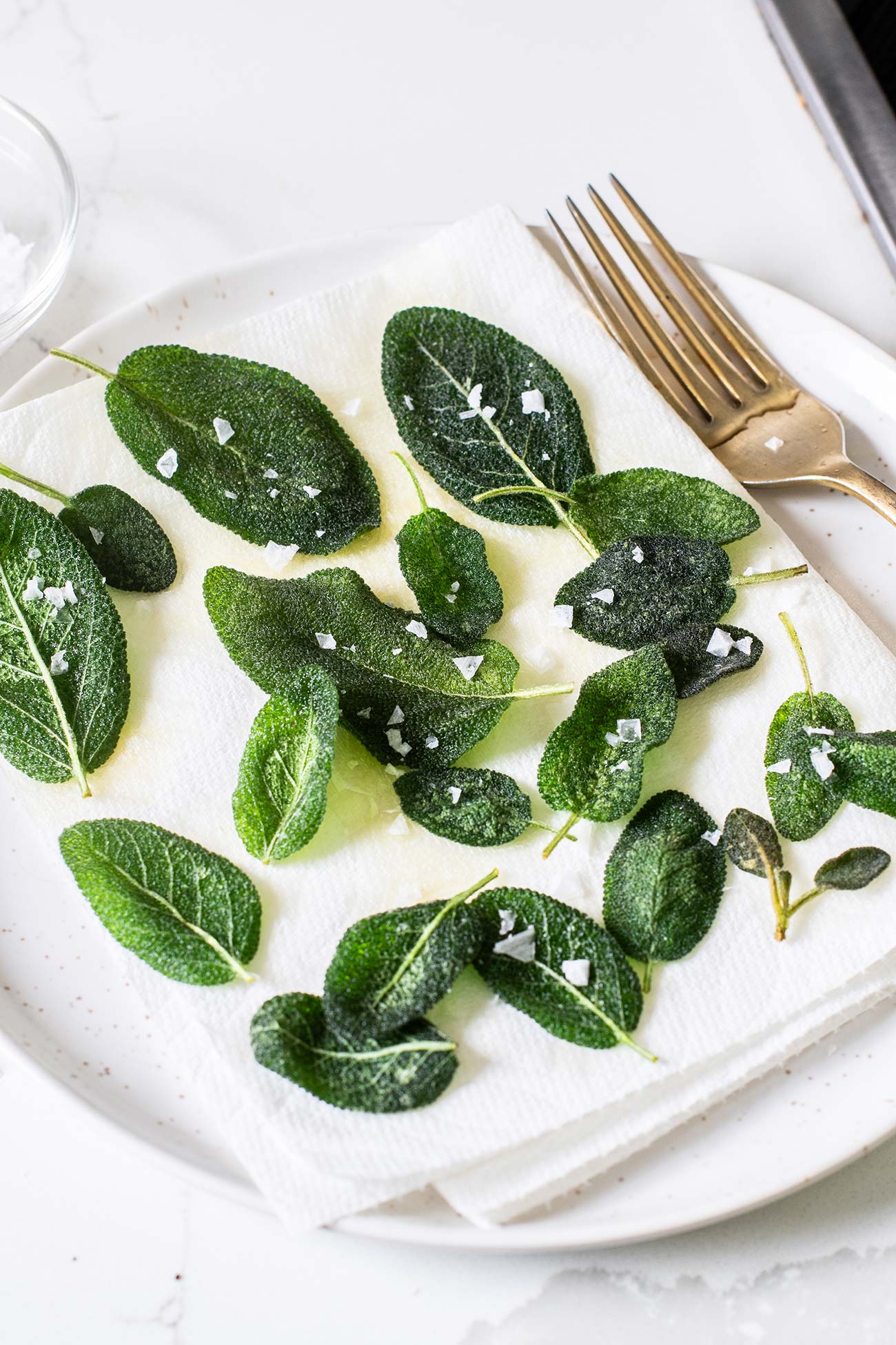 Fried sage shown sprinkled with flaky salt.