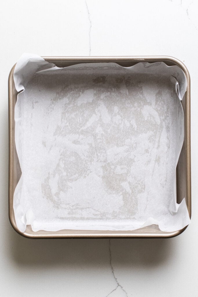 A 9x9 pan shown lined with parchment paper.