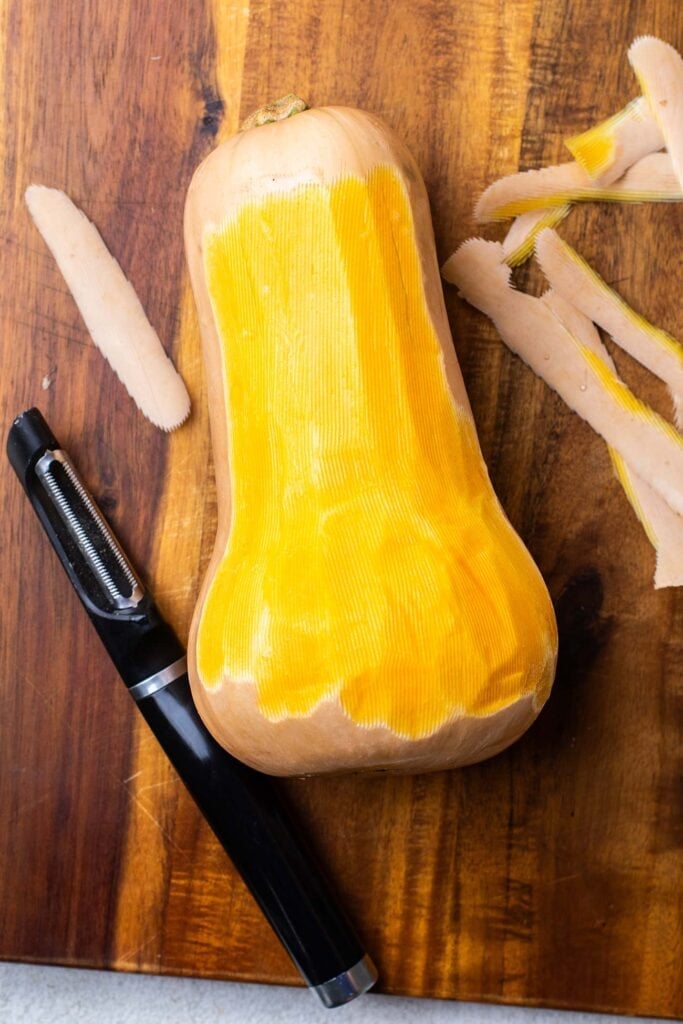 A butternut squash being peeled.