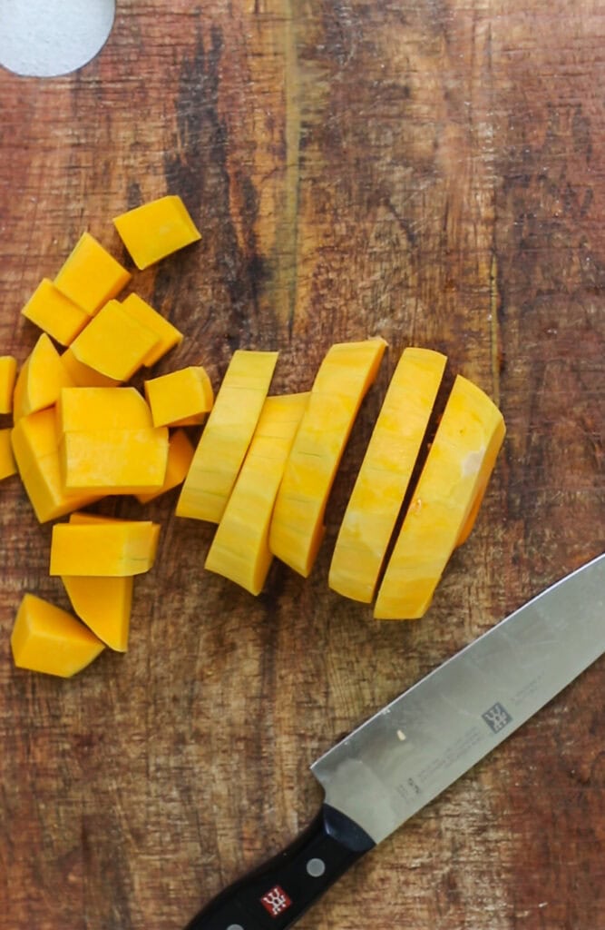 A squash being cut into 1 inch cubes.