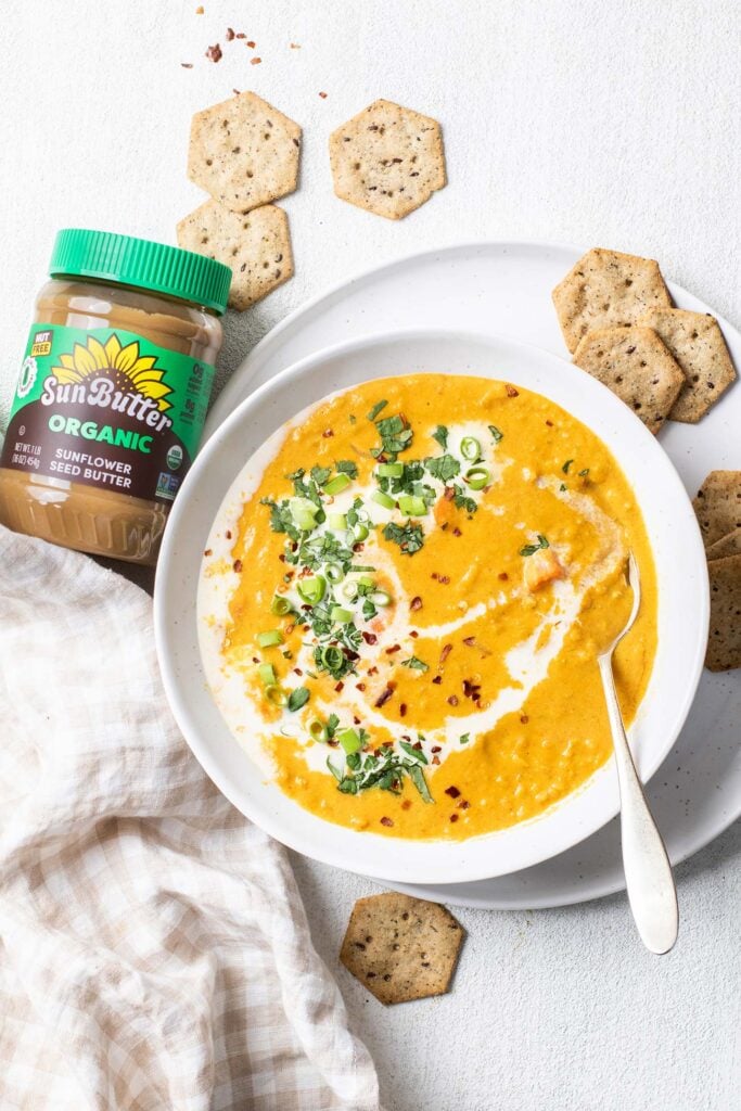 A jar of Organic SunButter next to a bowl of carrot and lentil soup.