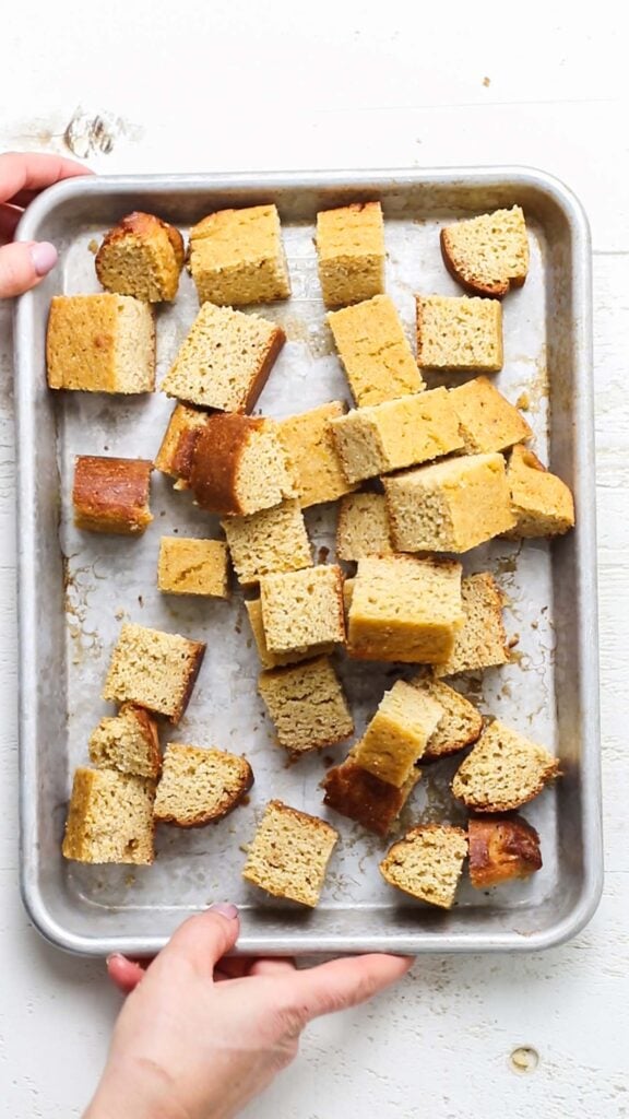 Cornbread cut into cubes and on a baking tray.