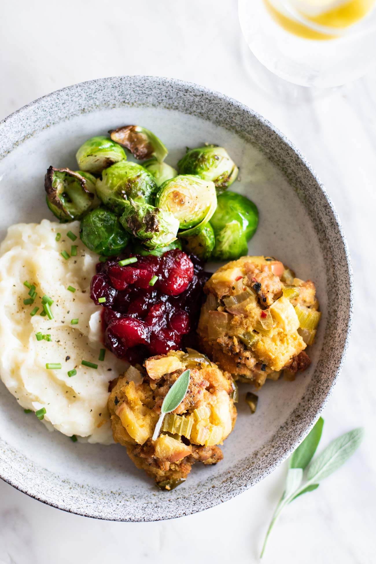 A plate shown with sausage stuffing balls, cranberry sauce, and brussels sprouts.