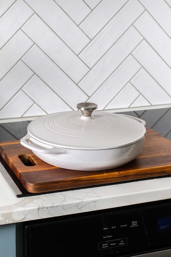 A cast iron braiser pan sitting on an oven.