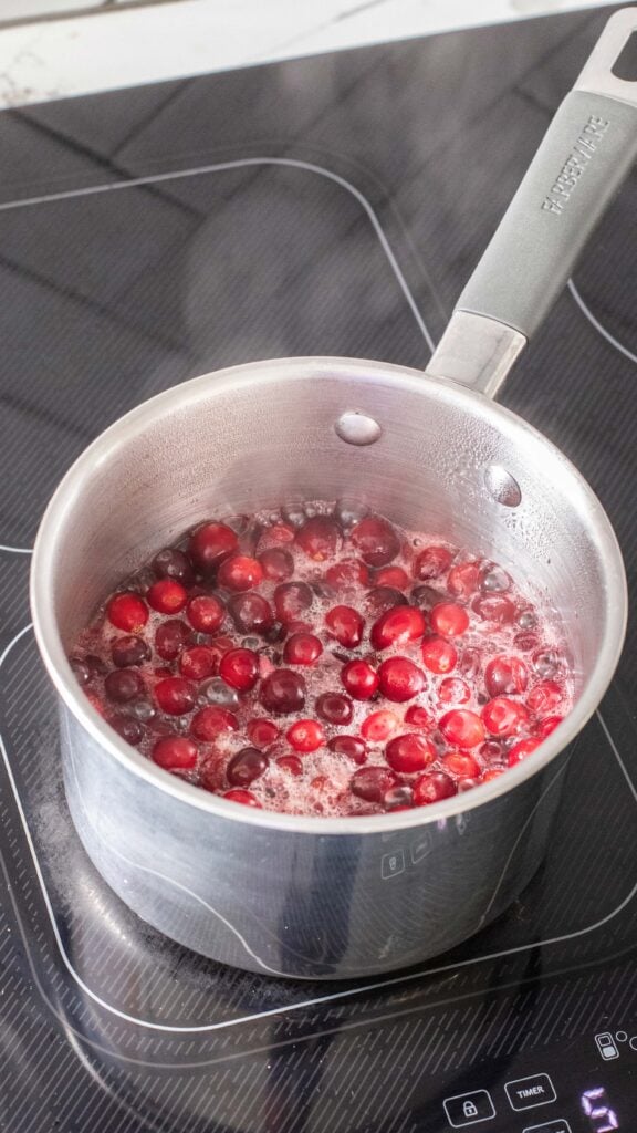 Cranberries boiling in a saucepan.