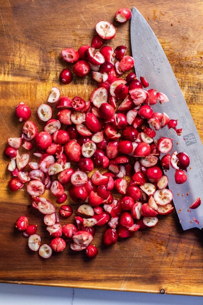 Fresh cranberries being chopped on a cutting board.