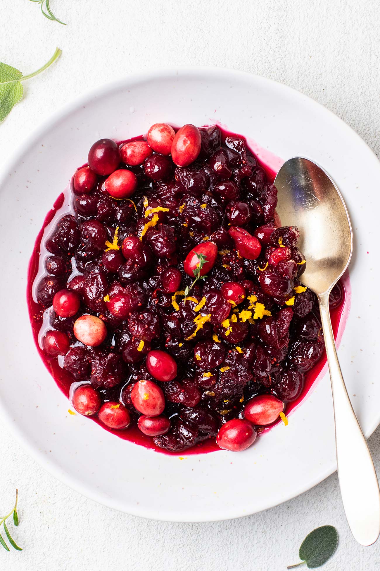 A bowl of cranberry sauce garnished with fresh thyme.