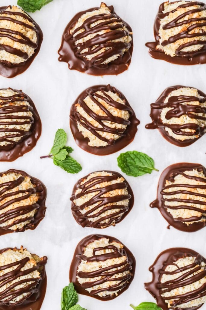 Macaroons shown on a baking sheet with a dark chocolate dip and drizzle.
