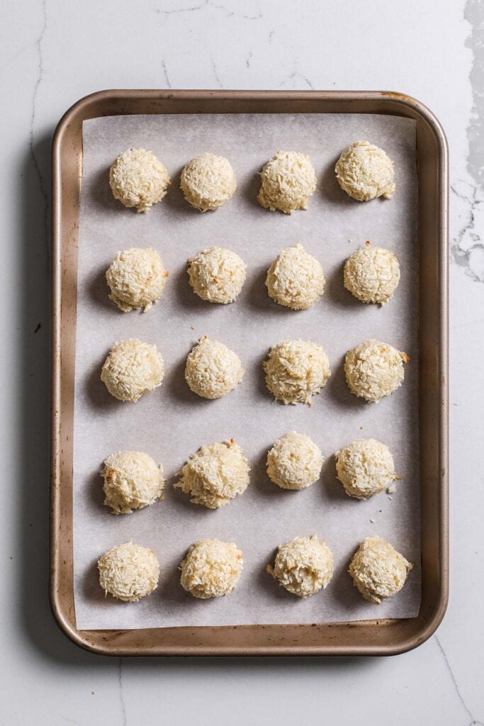 Lightly browned macaroon cookies on a baking sheet.