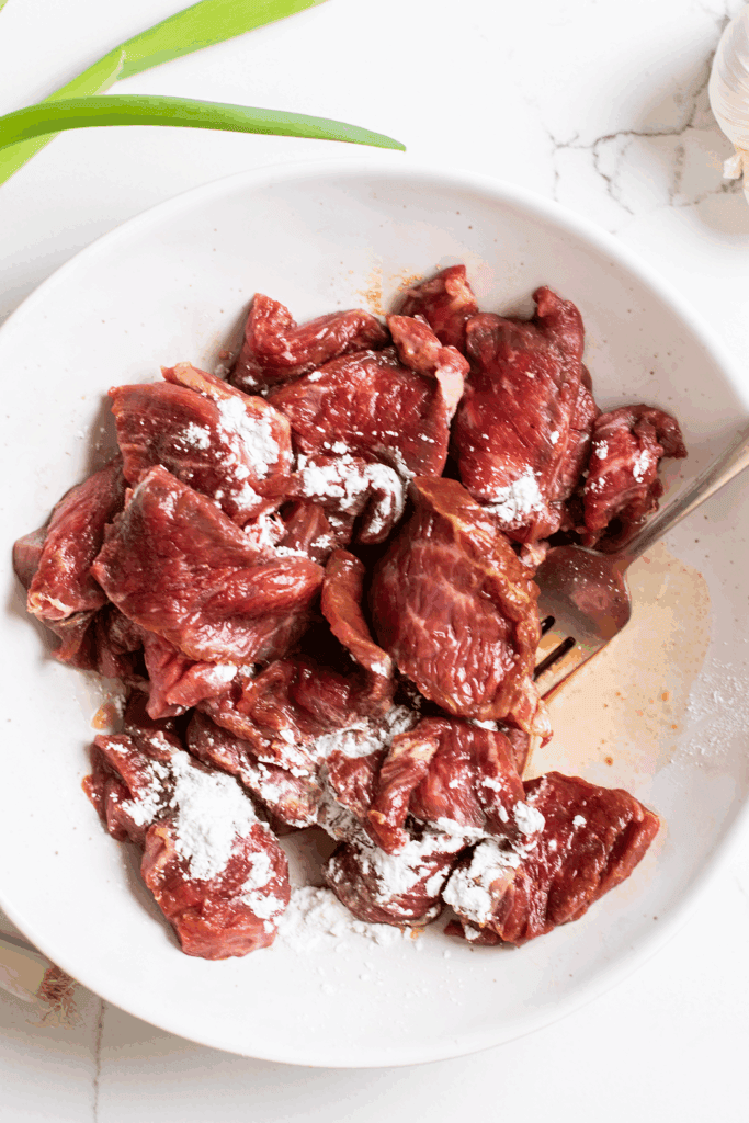 A bowl of thinly sliced beef sprinkled with arrowroot powder.
