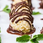 a close up look at a macaroon dipped in chocolate with a chocolate drizzle on top.