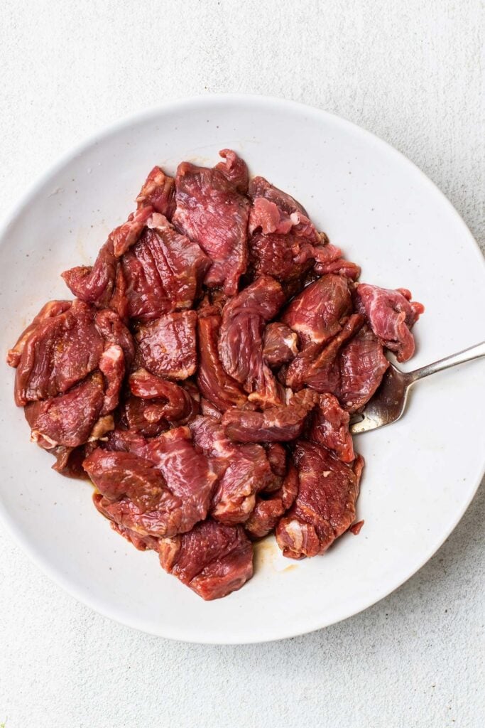 Thinly sliced steak in a bowl mixed with coconut aminos.