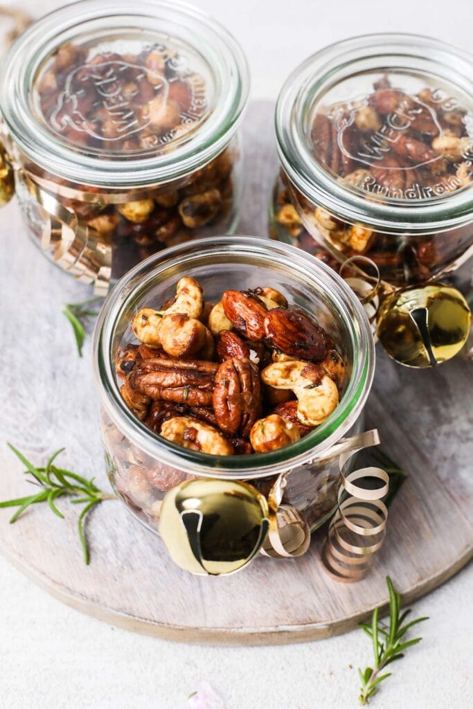 Spiced candied nuts shown in jars with ribbons, to use as gifts.