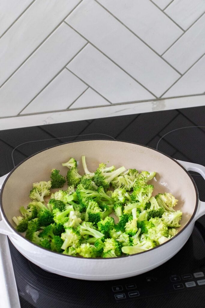 Broccoli being steamed in a large pan.
