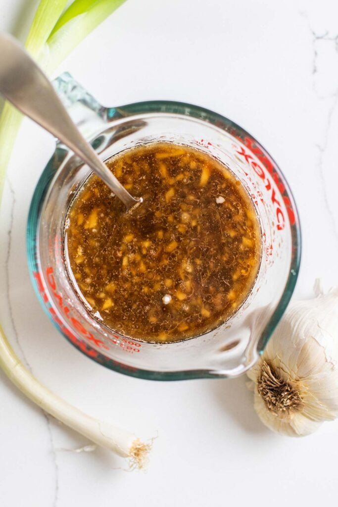A stir fry sauce being whisked together in a large measuring cup.