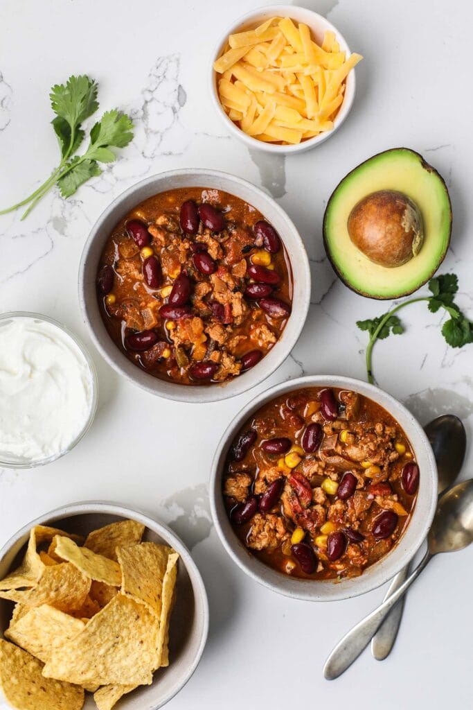 Two bowls of chili shown surrounded by topping suggestions.