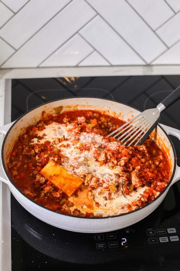 Adding heavy cream to the sauce.