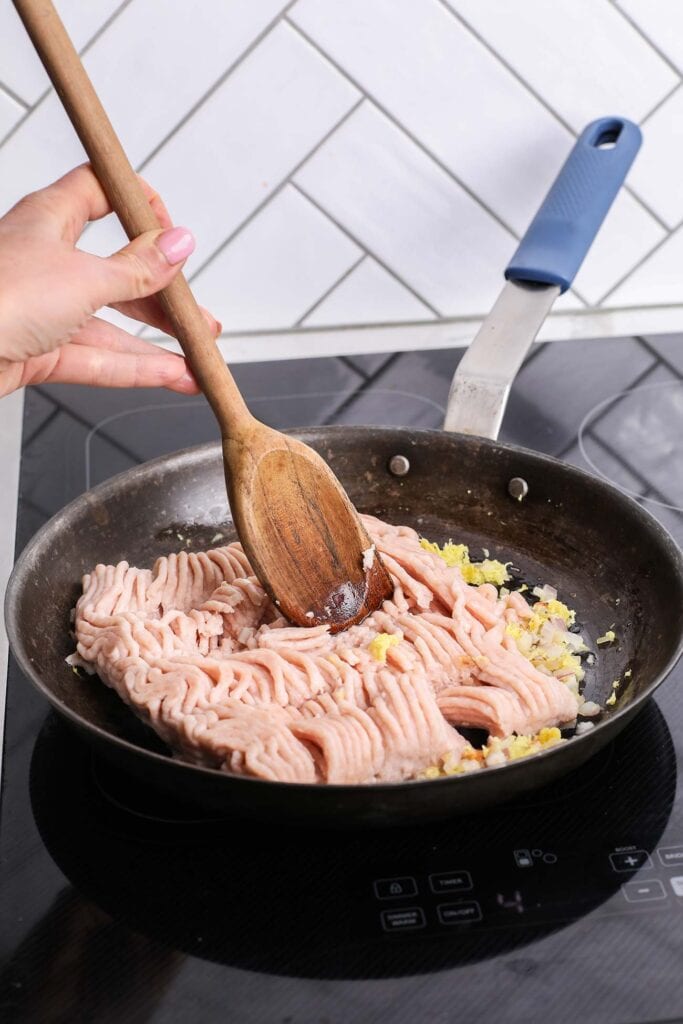 Ground chicken in a skillet being broken up and cooked.
