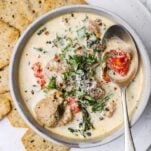 A bowl of a creamy soup with turkey meatballs, kale, and sundried tomatoes.