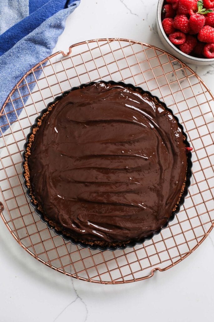 Chocolate ganache spread into an even layer in the tart crust.