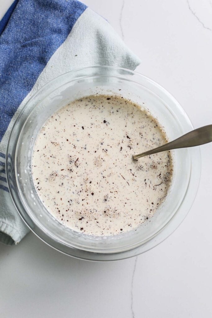 A bowl of dark chocolate with hot cream poured on top.