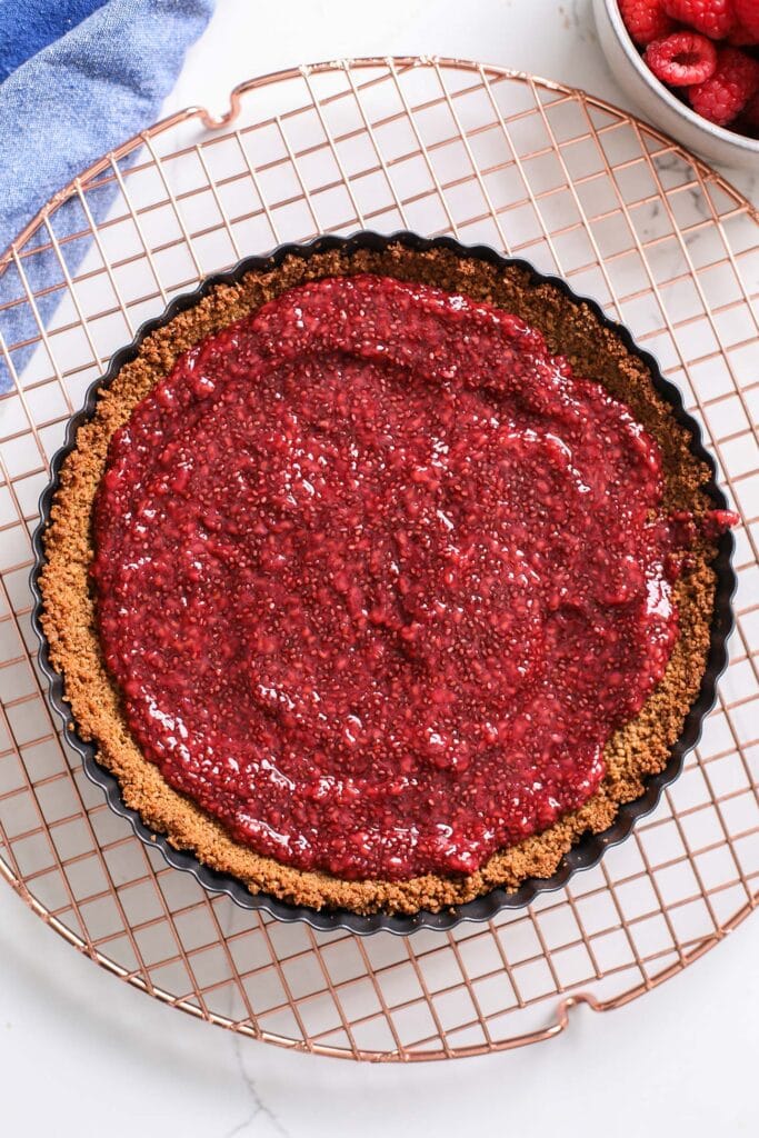 Raspberry jam spread into a thin layer in the prebaked crust.
