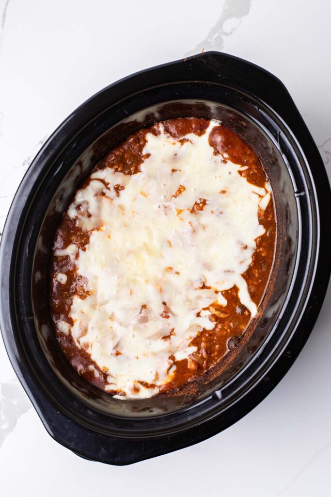 Chicken and brown rice cooked with cheese melted on top still in the slow cooker.