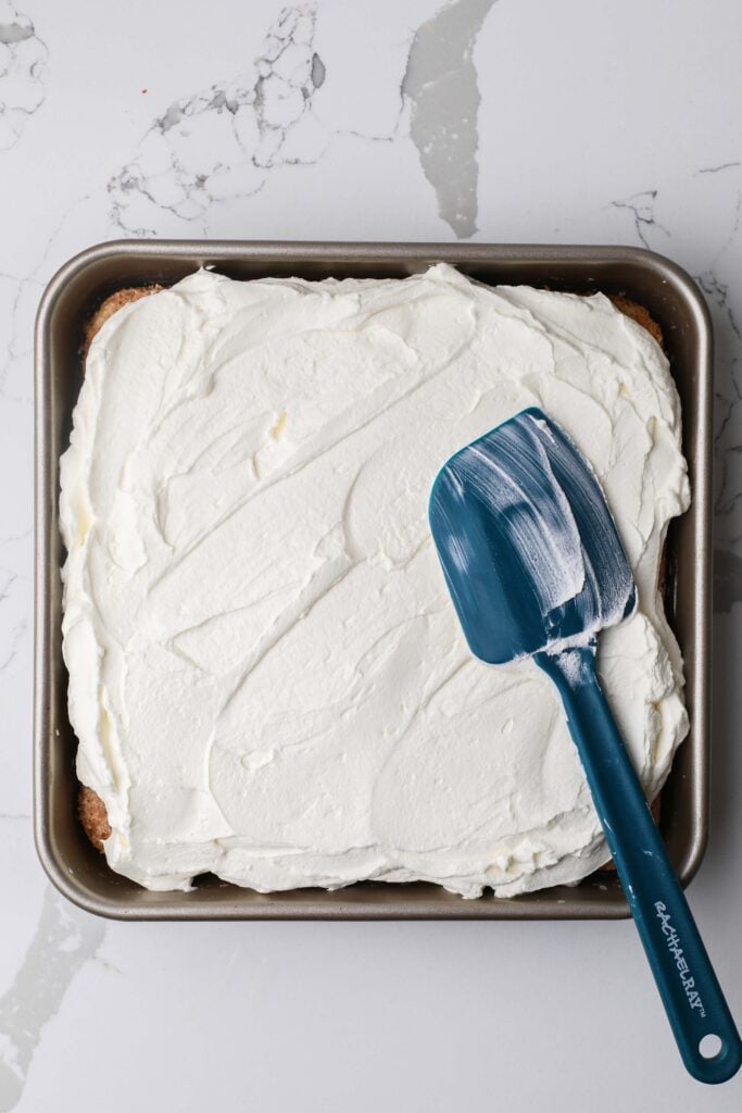 Topping the cake with whipped cream.
